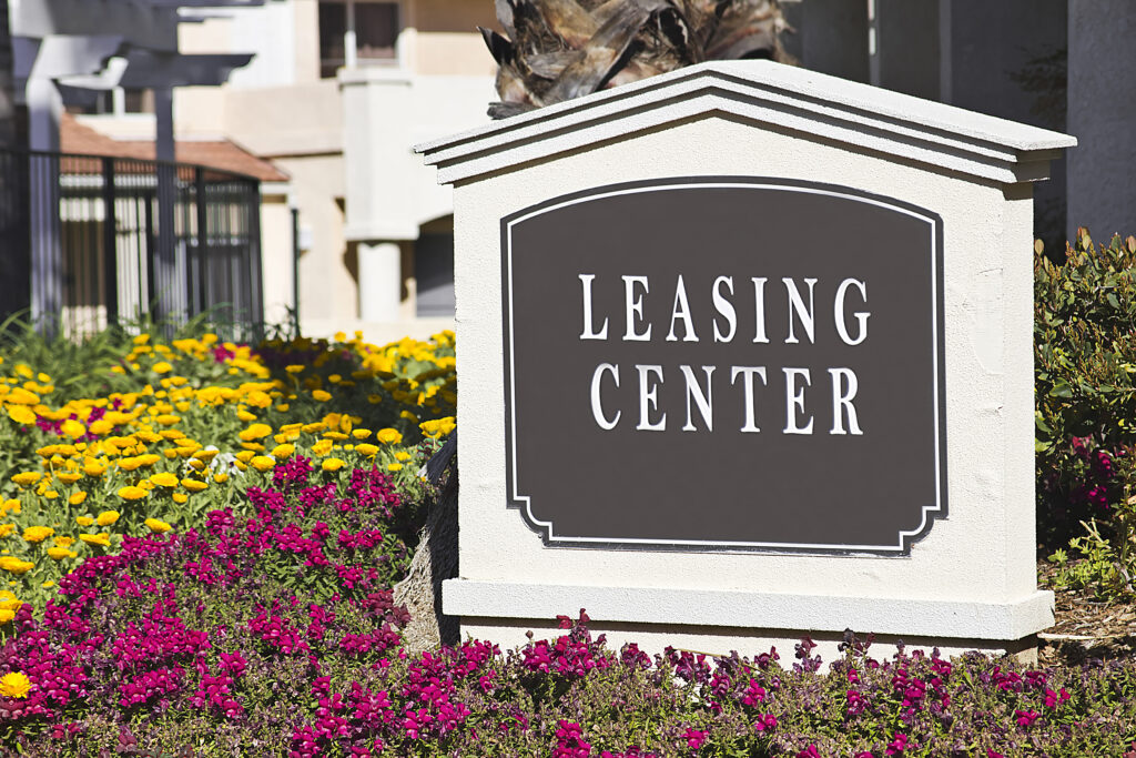 Leasing,Sign,Surrounded,By,Flowers,In,An,Apartment,Community.