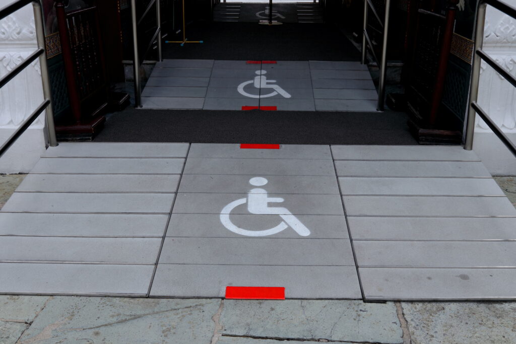 White sign of wheelchair on gray floor front doorway.